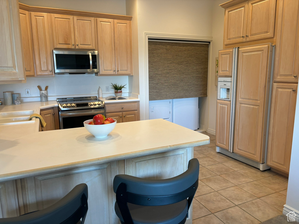 Kitchen with appliances with stainless steel finishes, kitchen peninsula, and light tile patterned floors