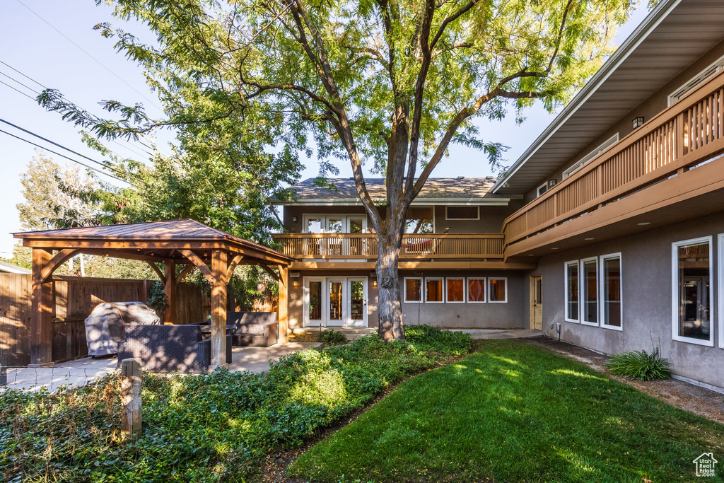 Rear view of property with french doors, a yard, a balcony, a gazebo, and a patio