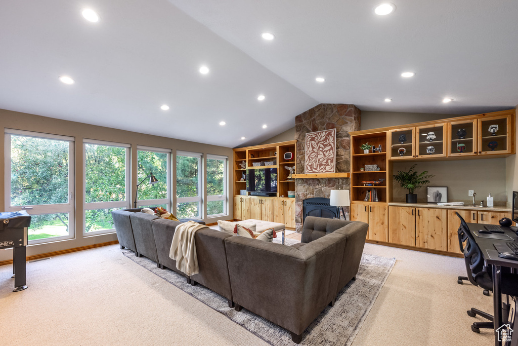 Carpeted living room with a stone fireplace and lofted ceiling