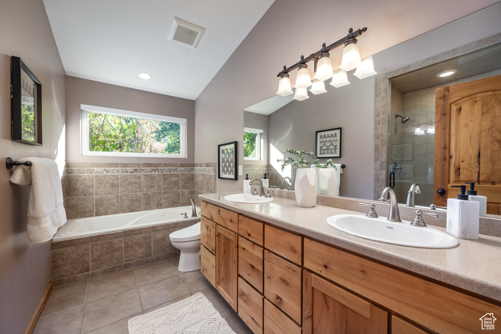 Full bathroom with lofted ceiling, tile patterned floors, toilet, independent shower and bath, and vanity