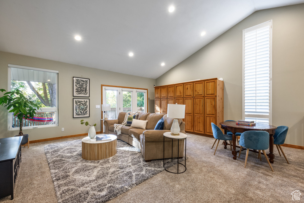 Living room featuring vaulted ceiling, light carpet, and a healthy amount of sunlight