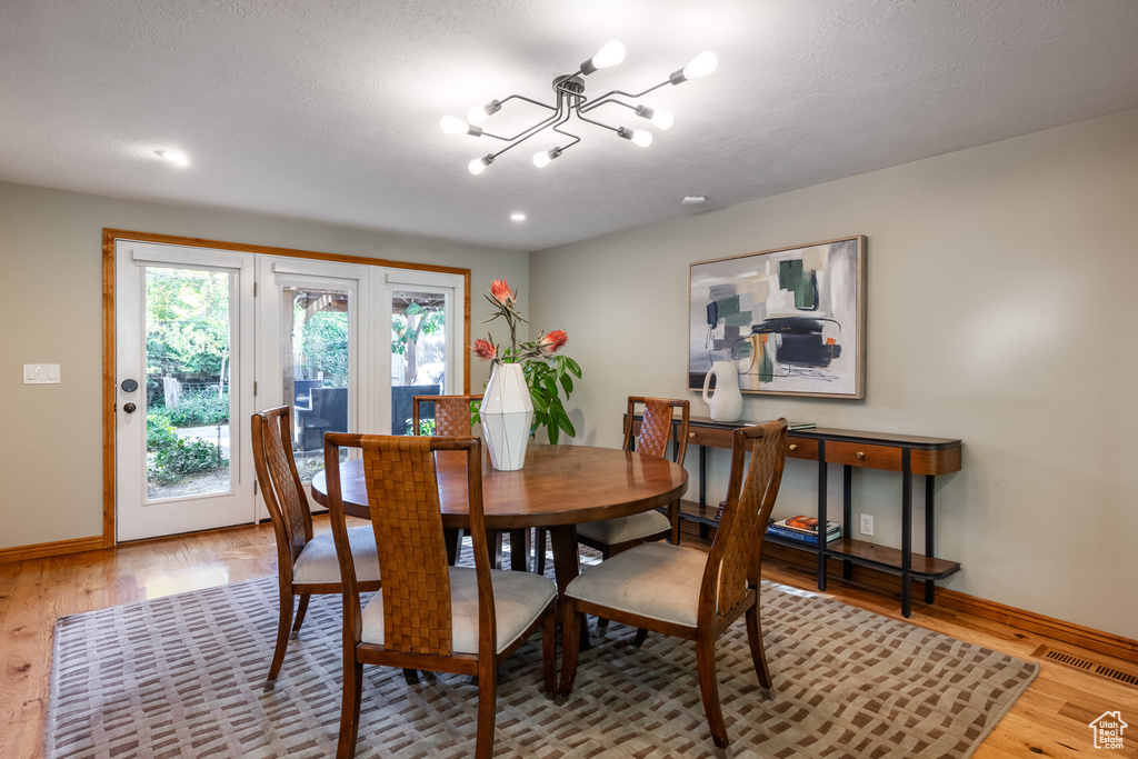 Dining area with a notable chandelier, wood-type flooring, and a textured ceiling