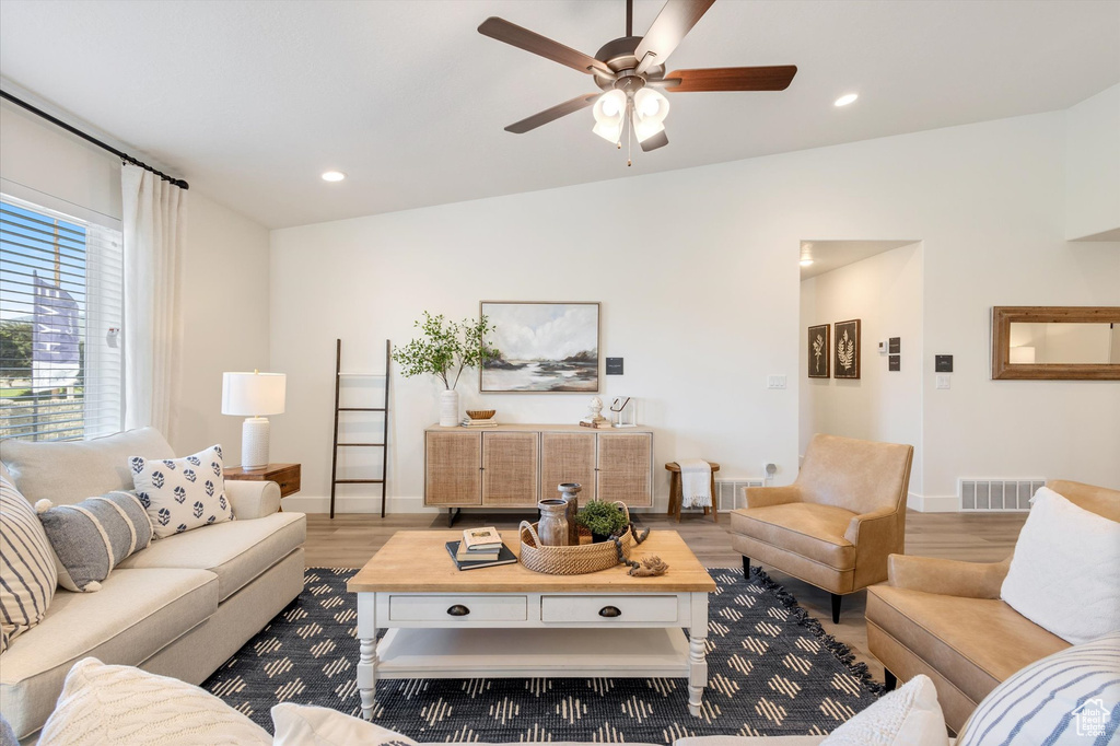 Living room with lofted ceiling, ceiling fan, and hardwood / wood-style flooring