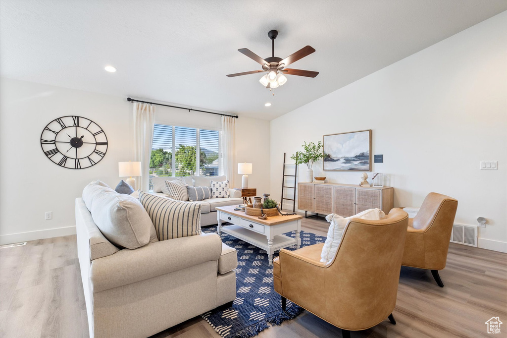 Living room featuring light wood-type flooring, vaulted ceiling, and ceiling fan