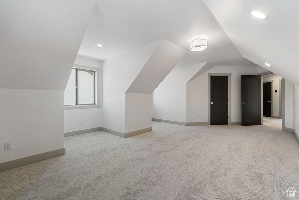 Bonus room with vaulted ceiling and light carpet