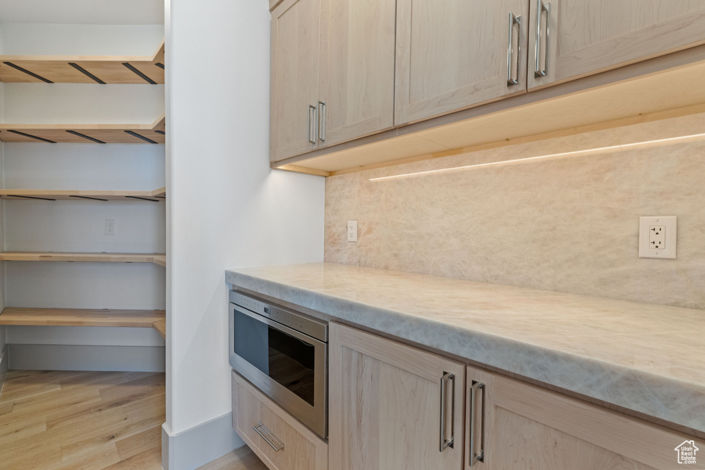 Kitchen featuring stainless steel microwave, light brown cabinetry, and light hardwood / wood-style flooring