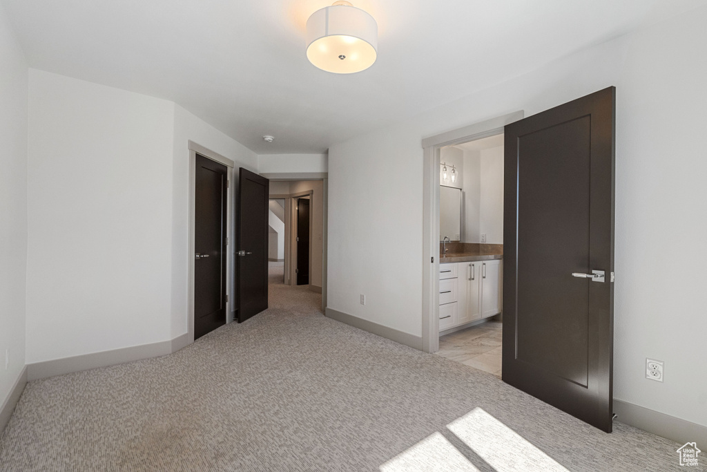 Unfurnished bedroom with light colored carpet and ensuite bath