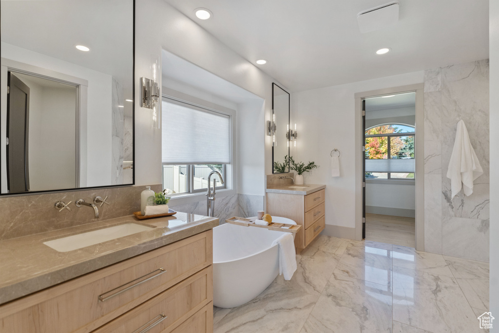 Bathroom featuring tile walls, vanity, and a tub