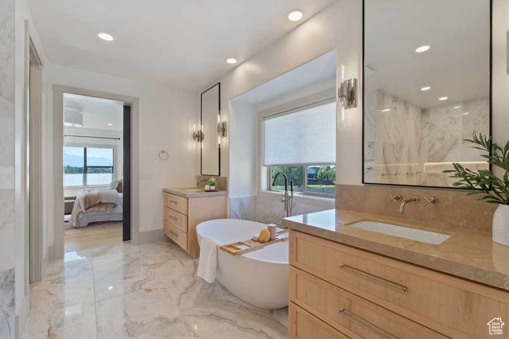 Bathroom with a wealth of natural light, a water view, vanity, and a bathing tub