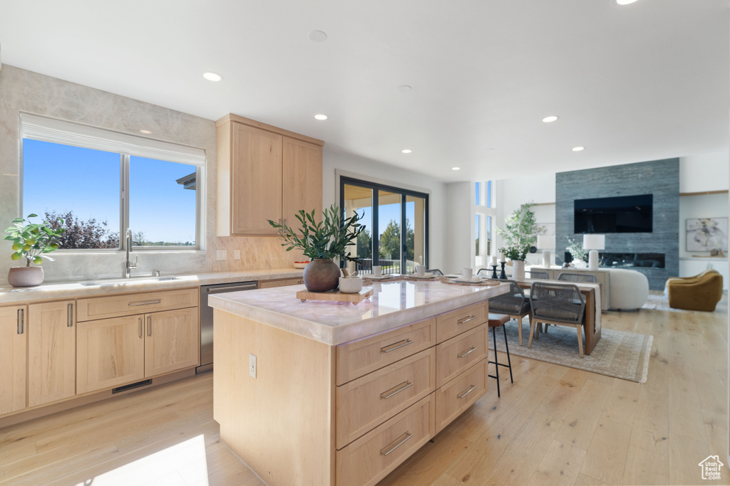 Kitchen with dishwasher, a center island, light brown cabinetry, a large fireplace, and a wealth of natural light