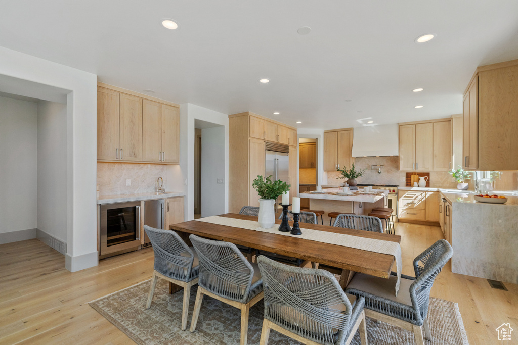 Dining room with light wood-type flooring, sink, and wine cooler