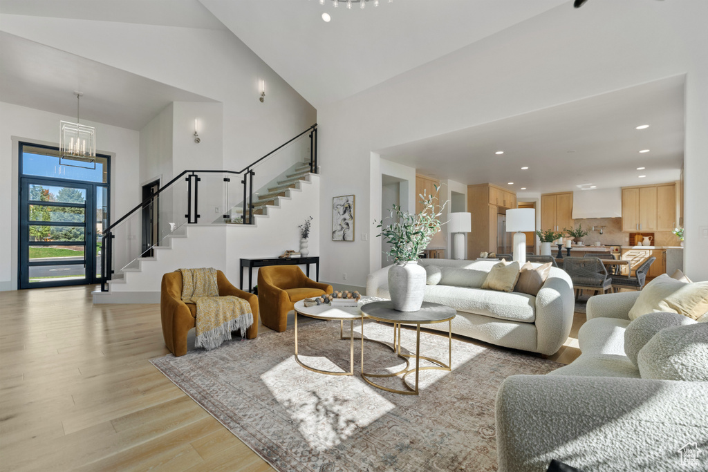 Living room featuring an inviting chandelier, light hardwood / wood-style flooring, and high vaulted ceiling