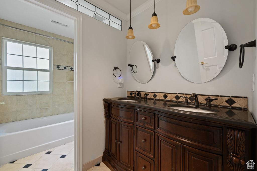 Bathroom with ornamental molding, a bath, and vanity