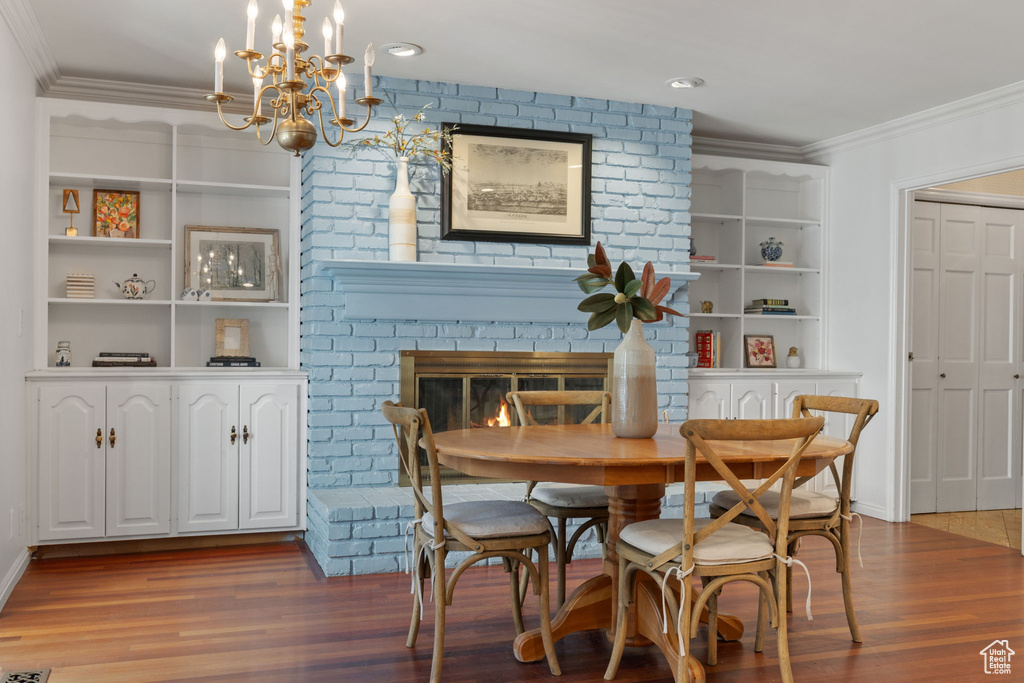 Dining area featuring a fireplace, ornamental molding, built in features, and hardwood / wood-style flooring