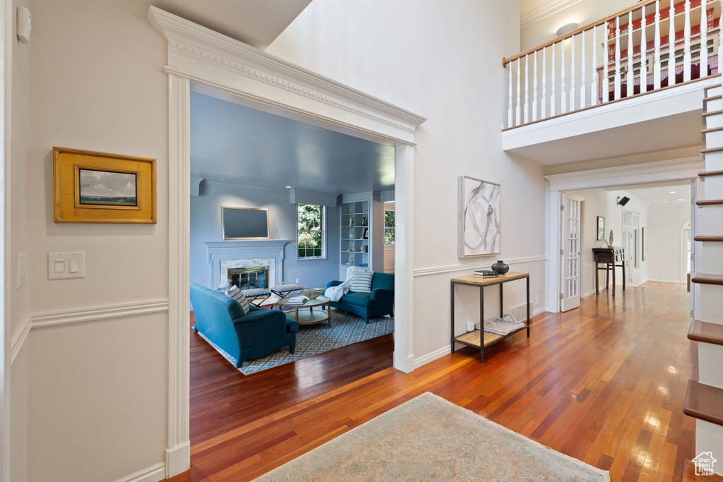 Entrance foyer with wood-type flooring, a high end fireplace, and a high ceiling