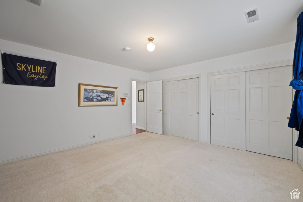 Unfurnished bedroom with light carpet and two closets