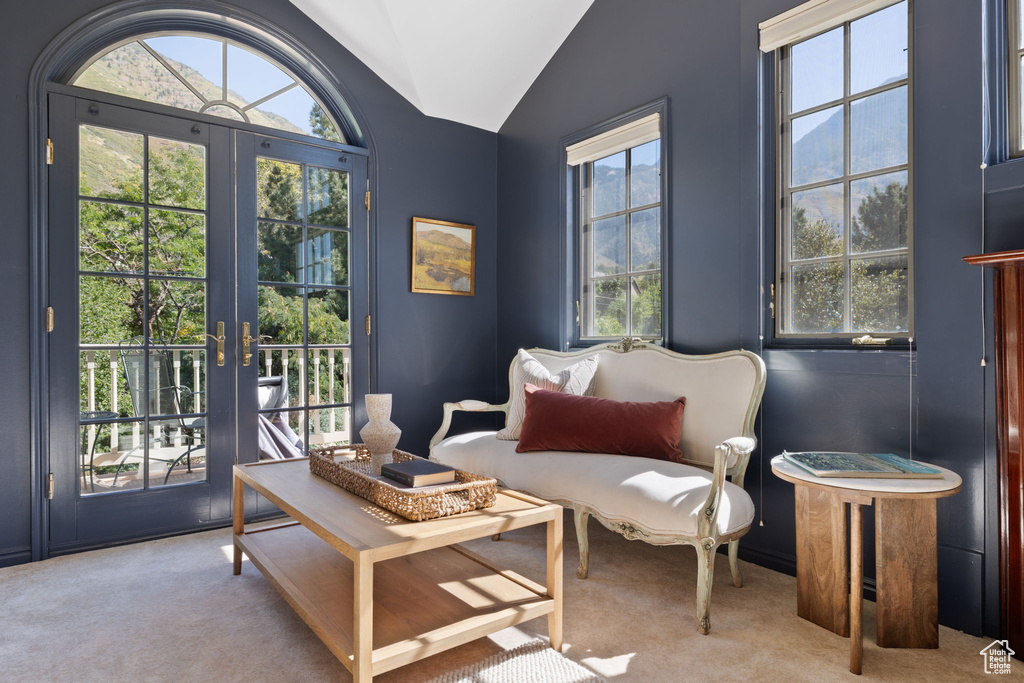 Living area with vaulted ceiling, light colored carpet, and french doors