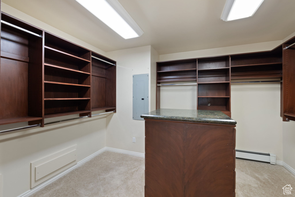 Spacious closet with light carpet, a baseboard radiator, and electric panel