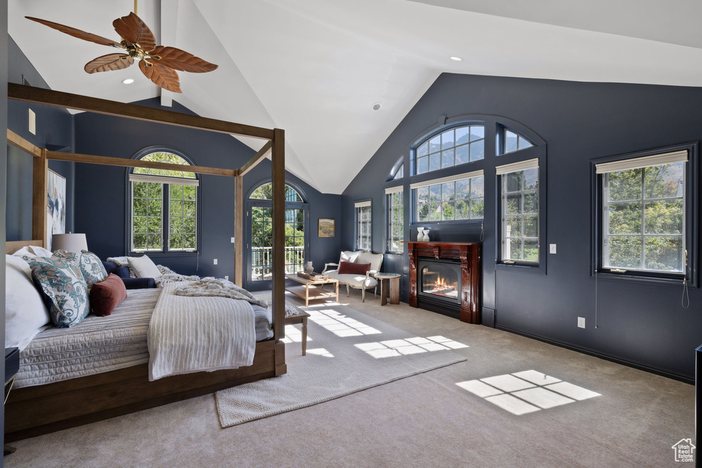 Carpeted bedroom featuring multiple windows, lofted ceiling, ceiling fan, and access to exterior