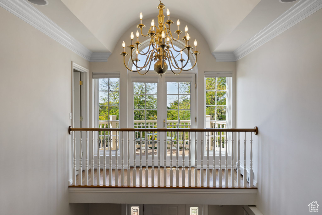 Interior space featuring a notable chandelier, crown molding, lofted ceiling, and plenty of natural light