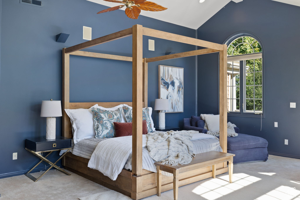 Carpeted bedroom with high vaulted ceiling and ceiling fan