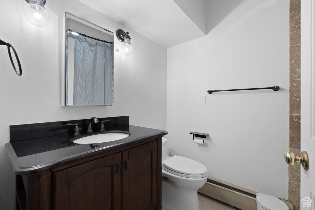 Bathroom with vanity, toilet, a baseboard heating unit, and a shower with shower curtain