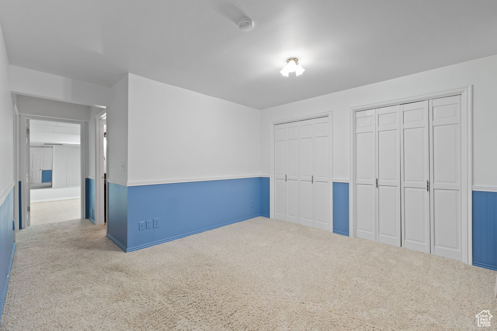 Unfurnished bedroom featuring carpet floors and two closets