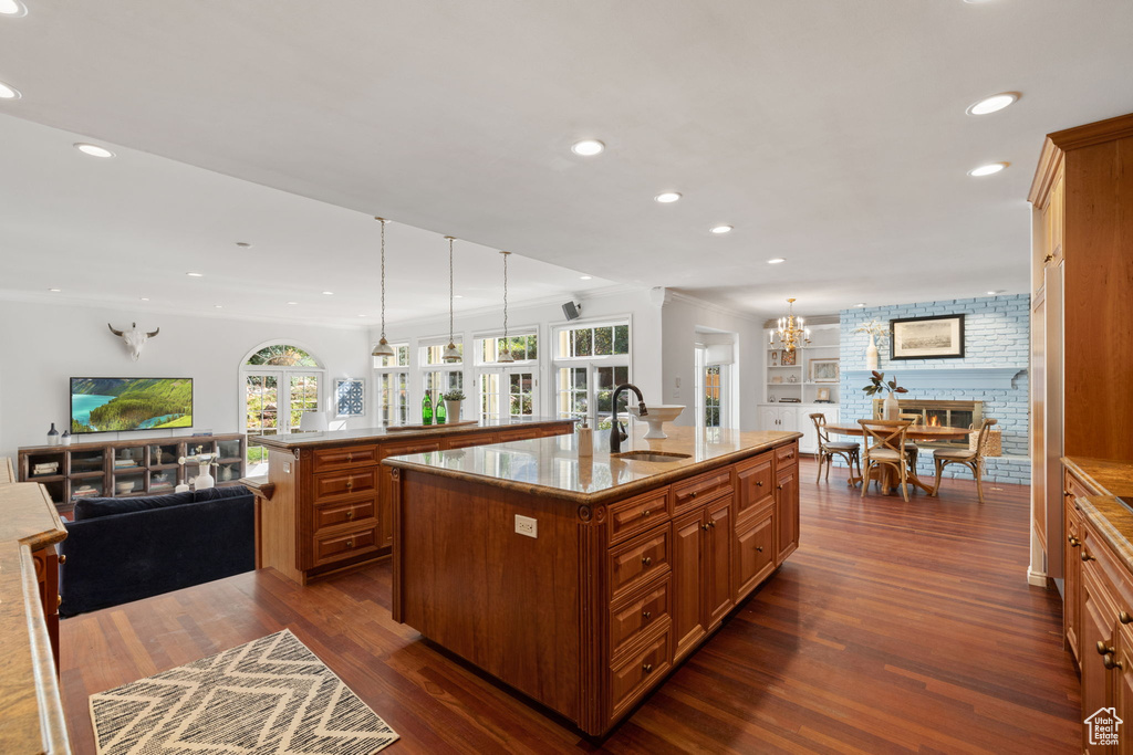 Kitchen with a spacious island, hanging light fixtures, dark hardwood / wood-style floors, and sink