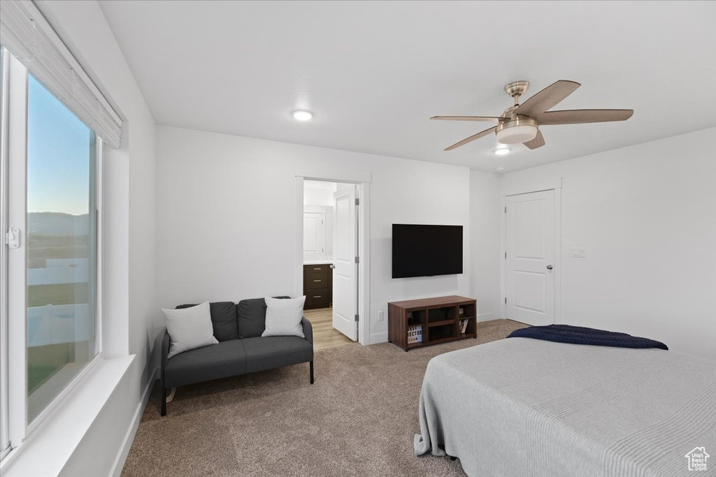 Carpeted bedroom featuring ceiling fan and ensuite bathroom