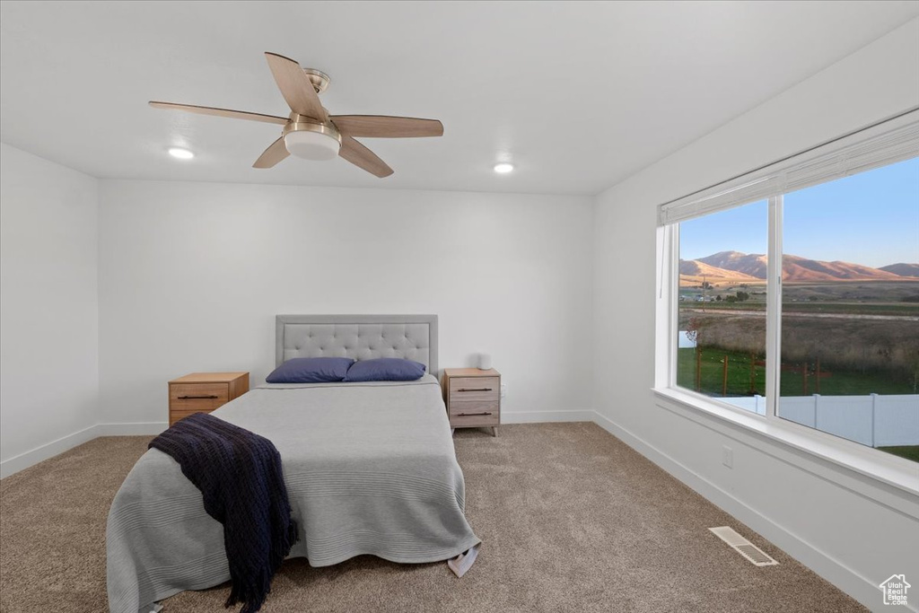 Carpeted bedroom with a mountain view and ceiling fan