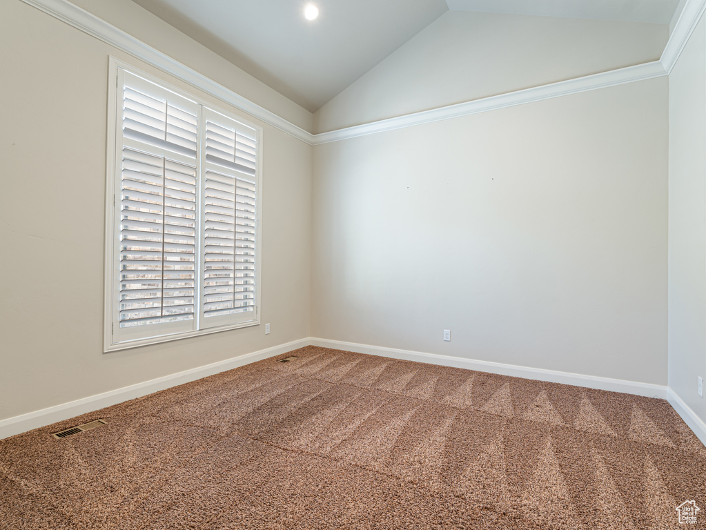 Spare room with lofted ceiling, baseboards, visible vents, and carpet