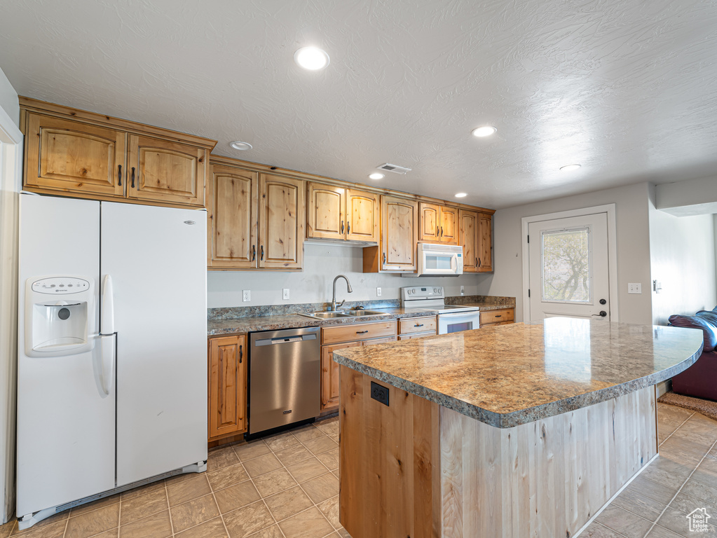 Kitchen featuring white appliances, recessed lighting, a sink, and a kitchen island