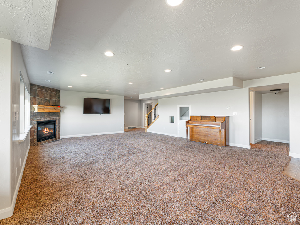 Unfurnished living room with a tile fireplace, stairway, baseboards, and recessed lighting