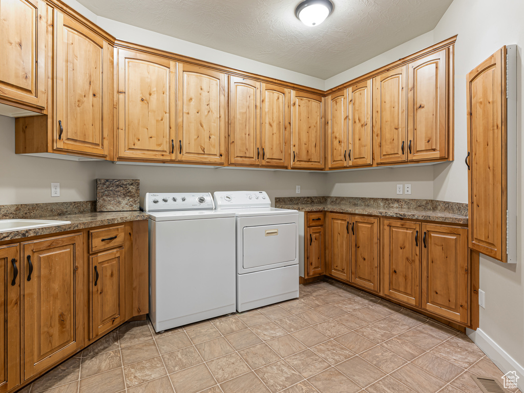 Washroom featuring washer and clothes dryer, cabinet space, and visible vents