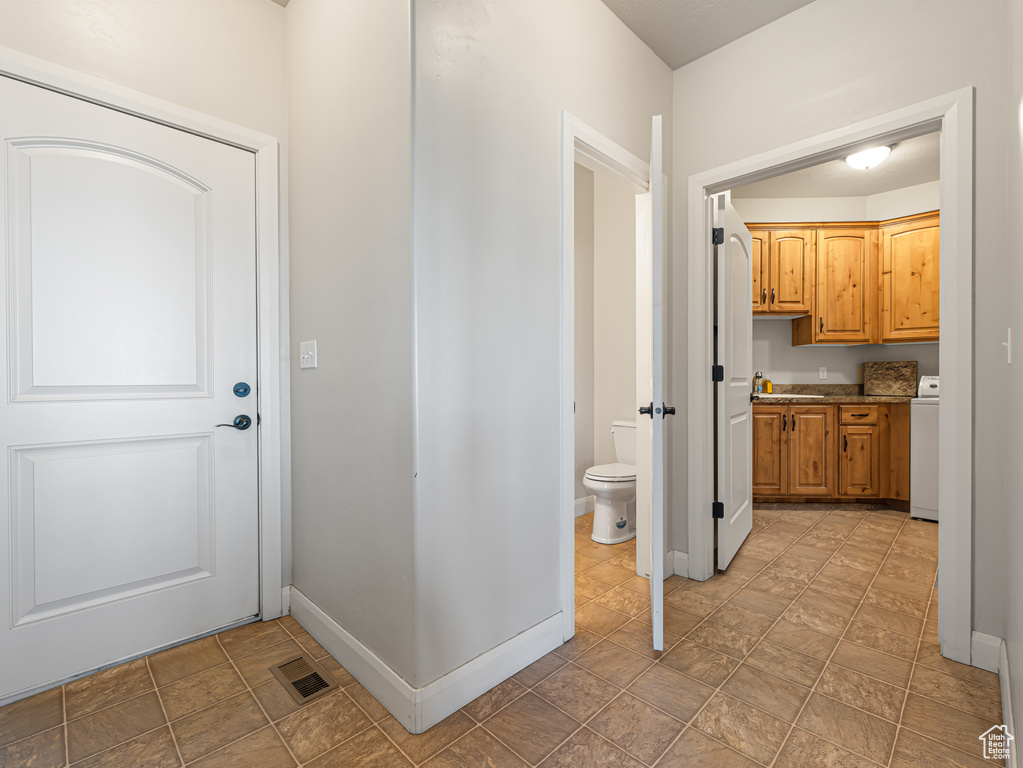 Interior space featuring baseboards, washer / dryer, stone finish flooring, and visible vents