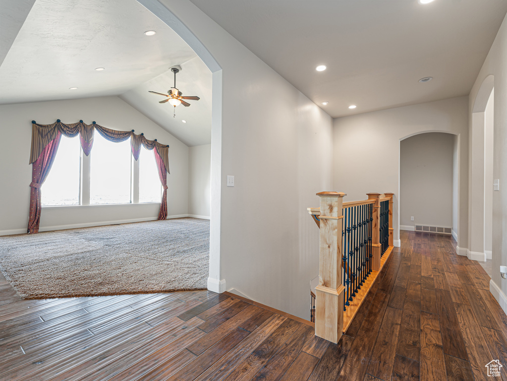 Corridor featuring recessed lighting, baseboards, hardwood / wood-style flooring, vaulted ceiling, and arched walkways