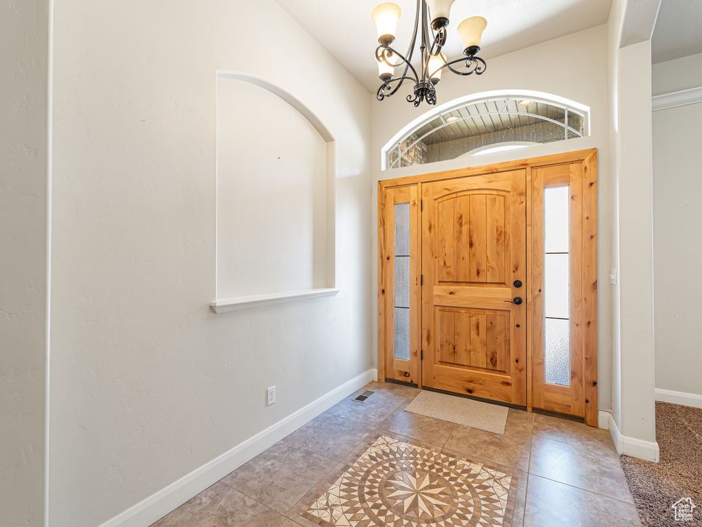 Foyer entrance featuring tile patterned flooring, a notable chandelier, and baseboards