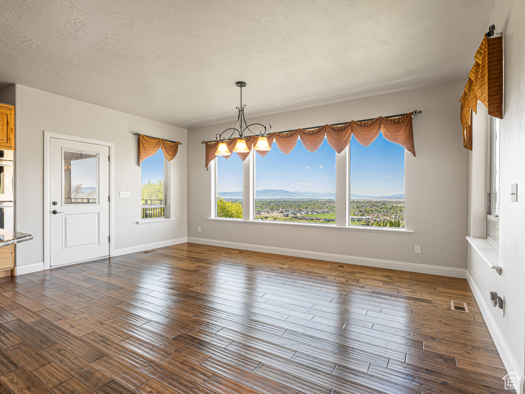 Unfurnished dining area featuring a chandelier, visible vents, baseboards, and dark wood-style floors