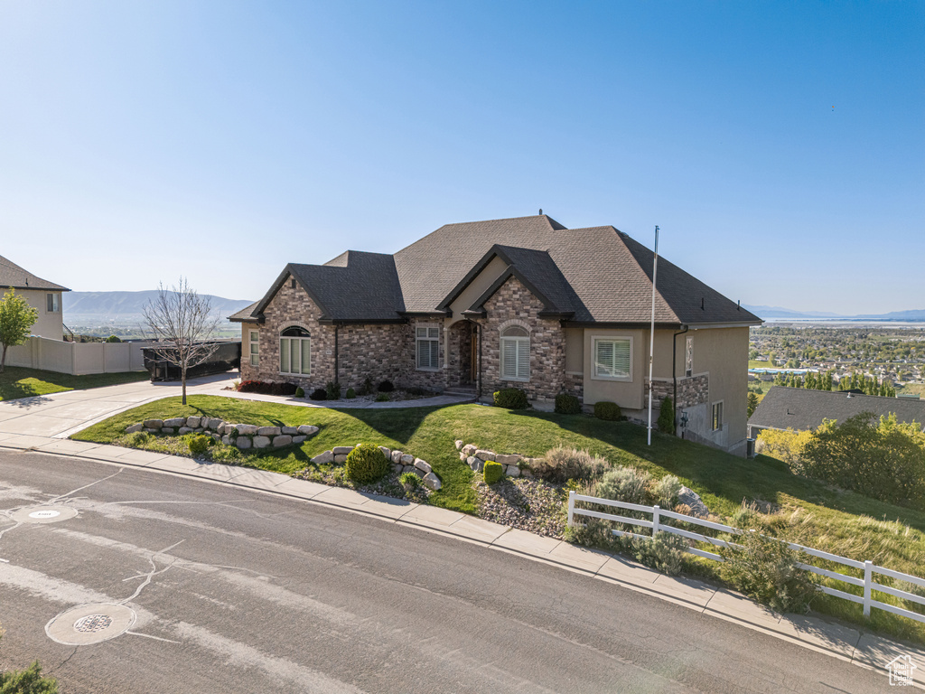 French country style house featuring fence, driveway, stone siding, and a front yard