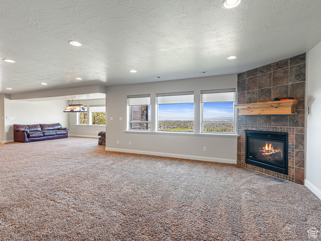 Unfurnished living room with recessed lighting, a textured ceiling, baseboards, carpet flooring, and a fireplace