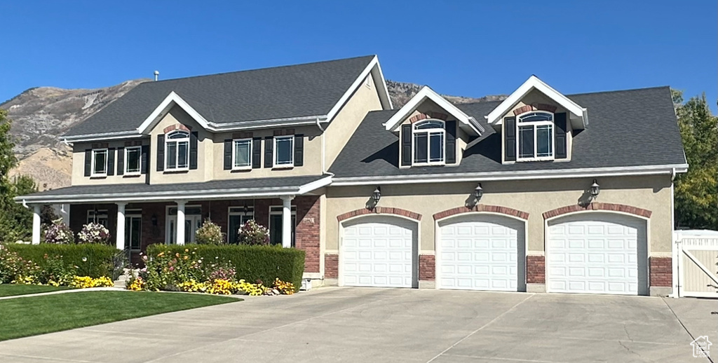 View of front of property featuring concrete driveway, brick siding, a porch, a mountain view, and an attached garage