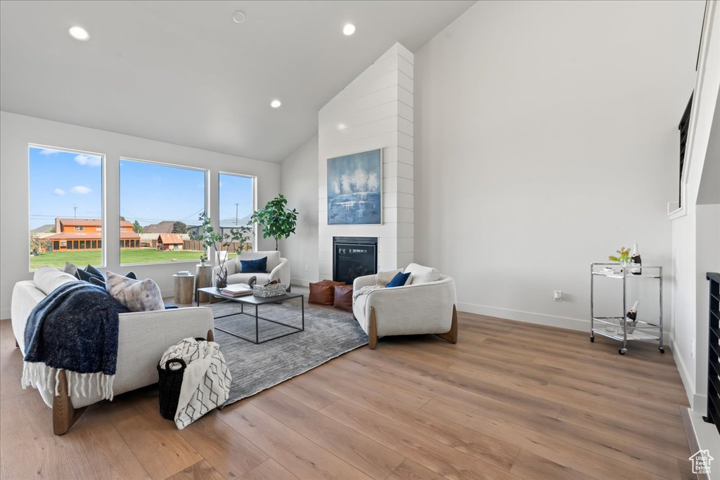 Living room featuring a fireplace, light hardwood / wood-style floors, and high vaulted ceiling