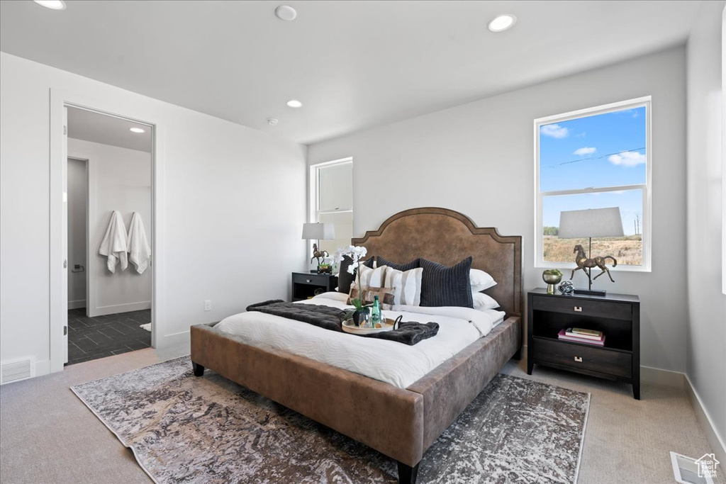 Bedroom with ensuite bath and light colored carpet