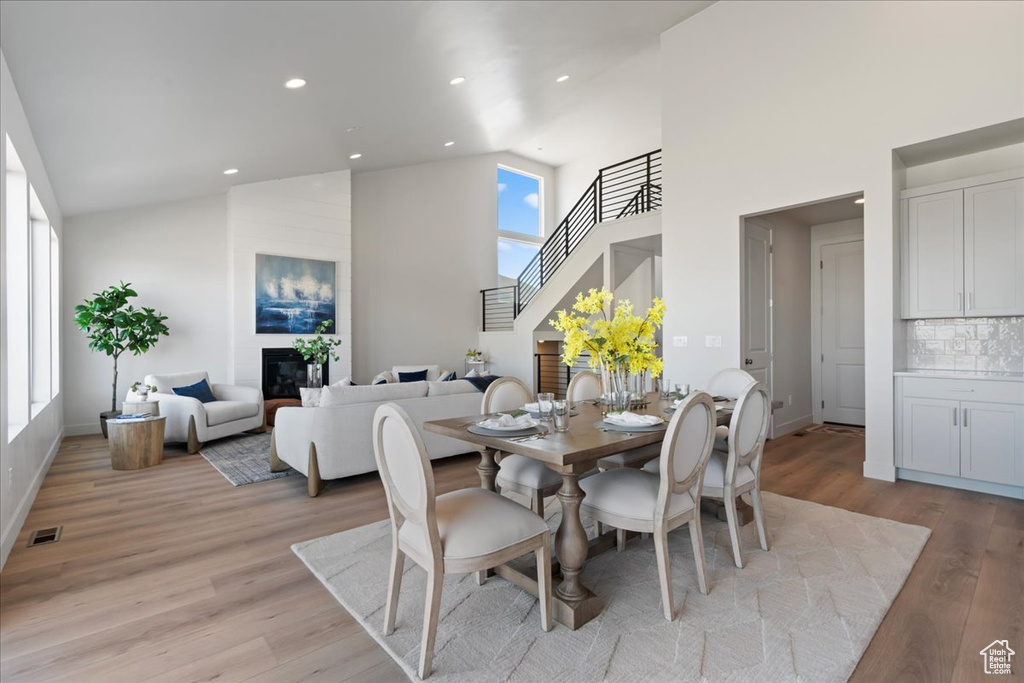 Dining room featuring high vaulted ceiling, light wood-type flooring, and a large fireplace