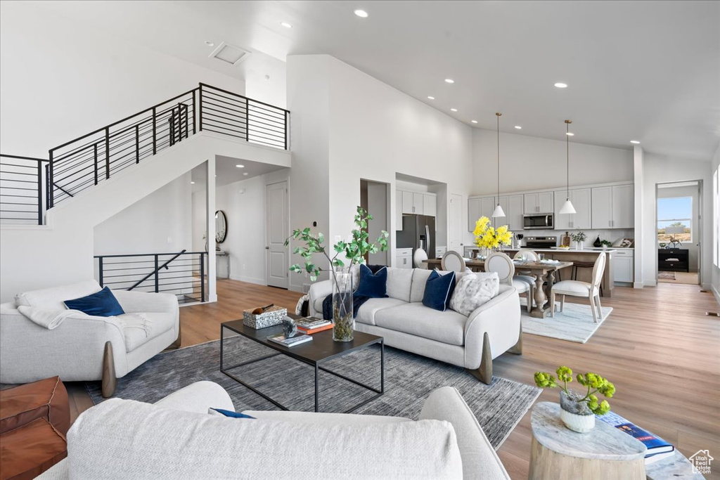 Living room with high vaulted ceiling and light wood-type flooring