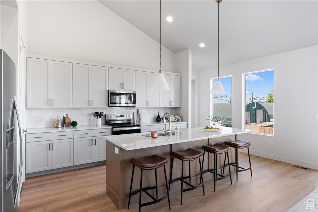 Kitchen with decorative light fixtures, a kitchen island with sink, stainless steel appliances, and sink