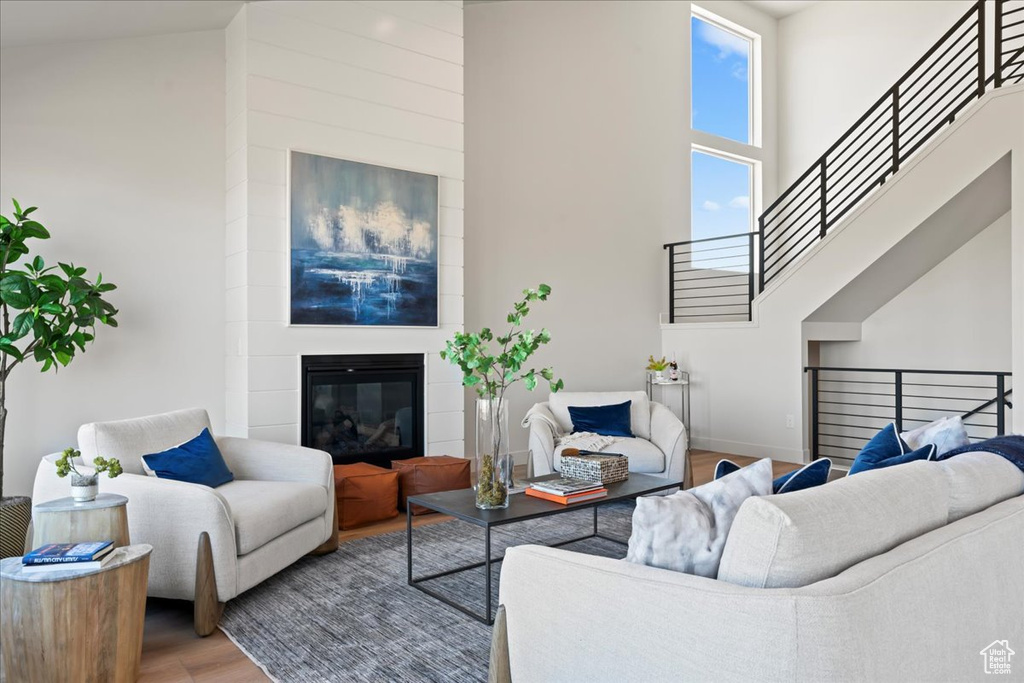 Living room with wood-type flooring, a towering ceiling, and a fireplace