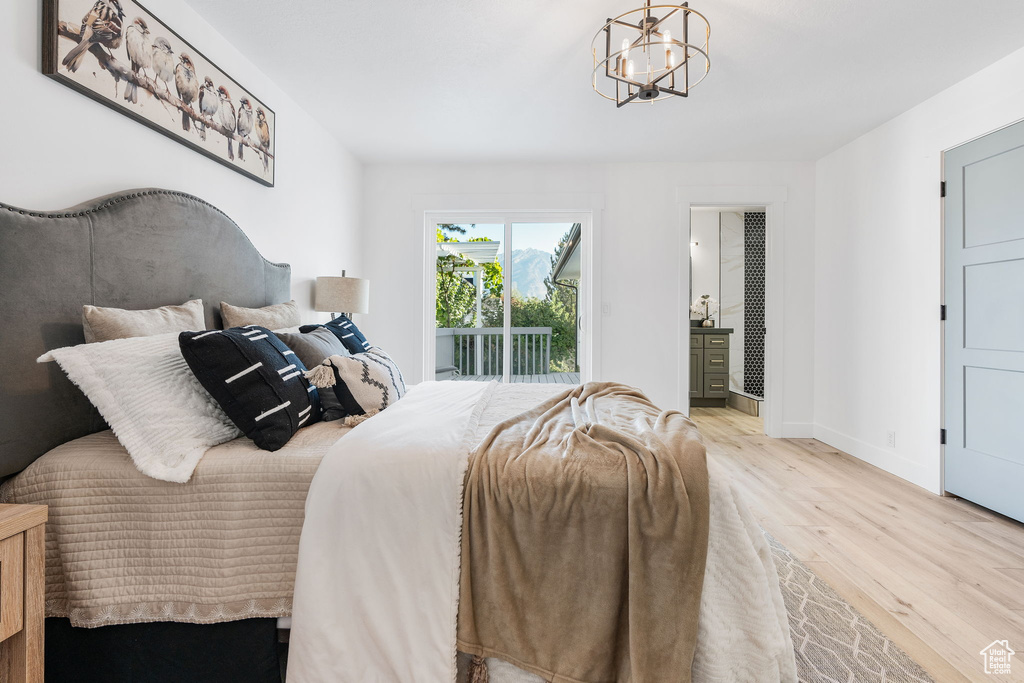 Bedroom with an inviting chandelier, light wood-type flooring, ensuite bath, and access to exterior