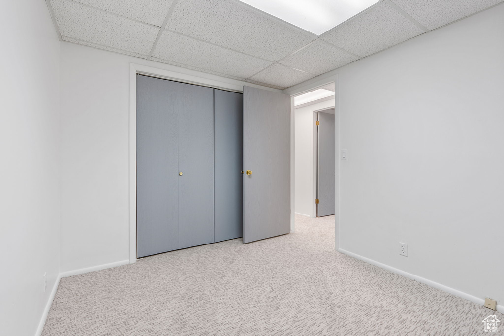 Unfurnished bedroom with a drop ceiling, carpet flooring, and a closet