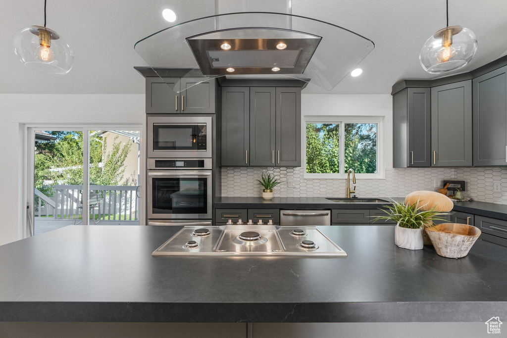 Kitchen with a wealth of natural light, appliances with stainless steel finishes, tasteful backsplash, and sink